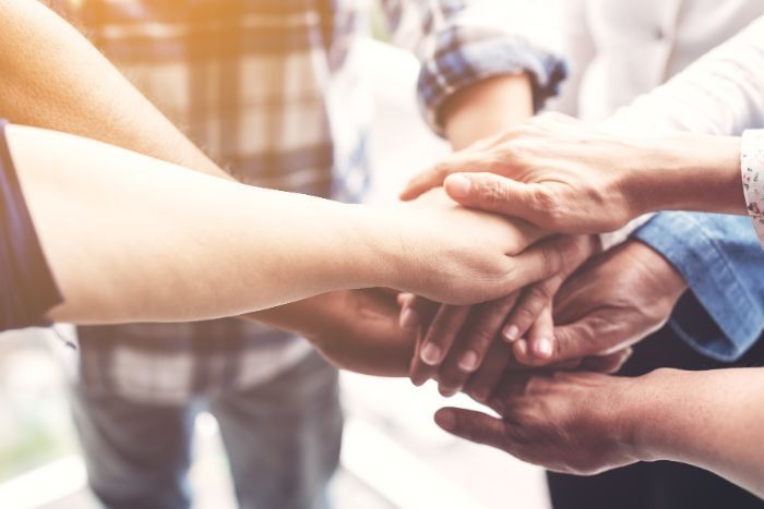 group of people with their hand in the center