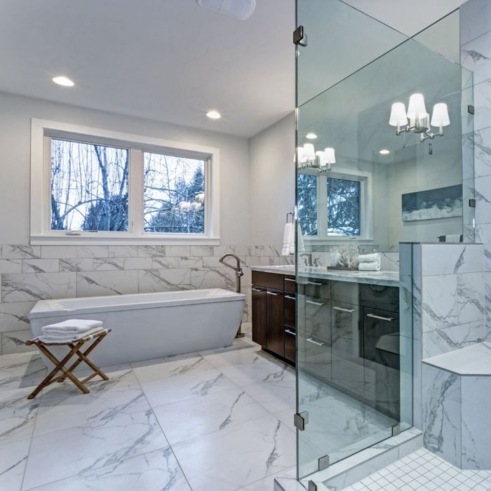 Luxurious bathroom with a freestanding bathtub, glass-enclosed shower, and marble-patterned tiles.