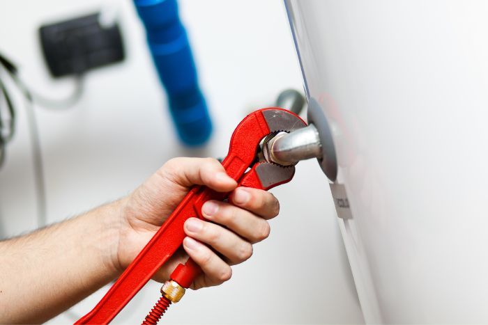 a person using a wrench on a water heater