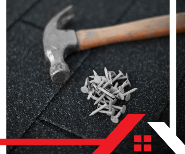 closeup of a hammer and nails on roof tiles