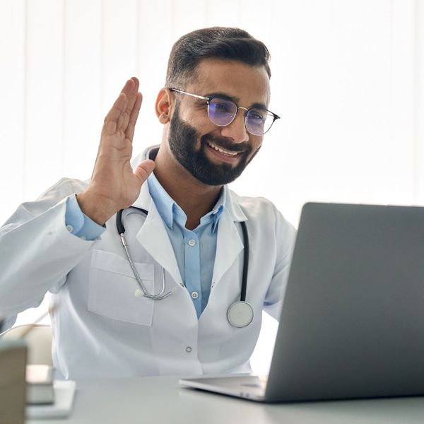 a doctor waving at a laptop