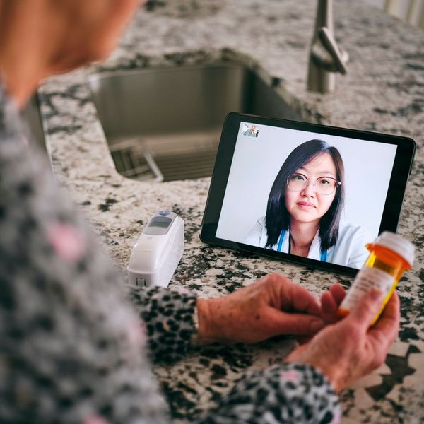 an elderly person talking with a doctor on a tablet while looking at medication