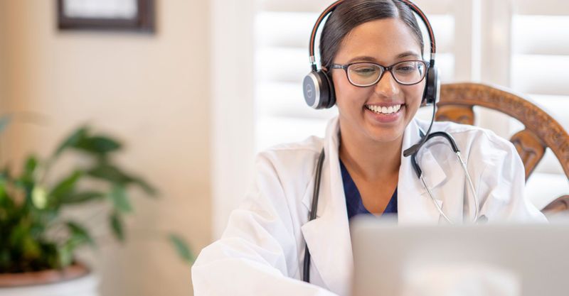 Doctor wearing headphones and using laptop for video chat