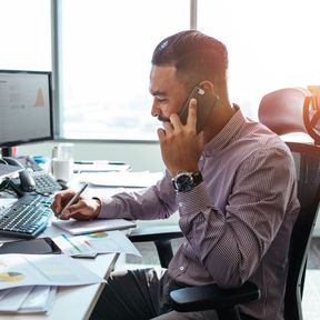 man on phone at desk, taking notes