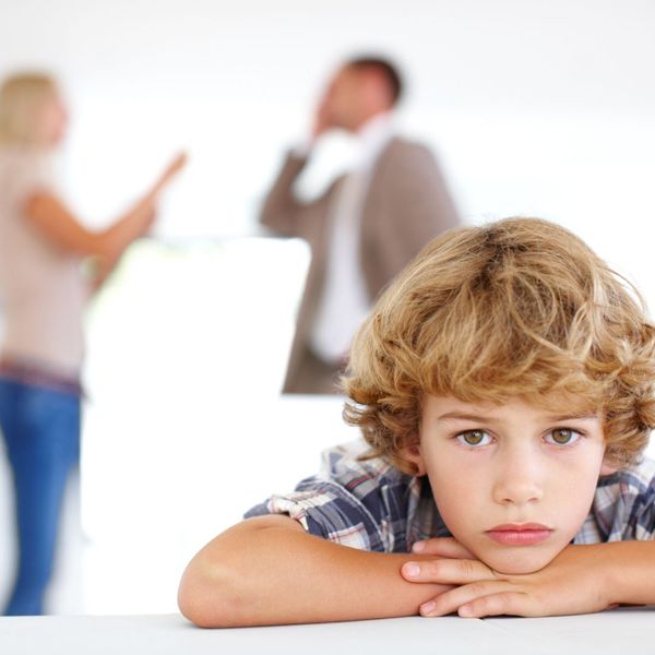Kid looking sad while parents fight in background