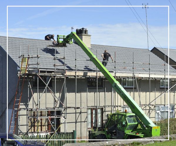 A large roof installation job being conducted on an apartment complex using a crane