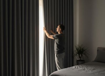 person closing curtains to block out the sun