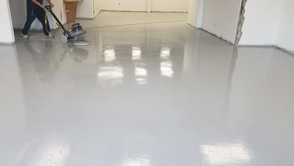 worker applying epoxy in a basement