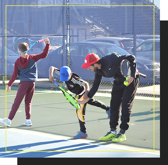Trainer working with a child on their tennis swing