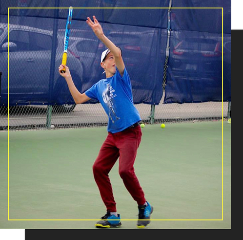 Youth serving a tennis ball