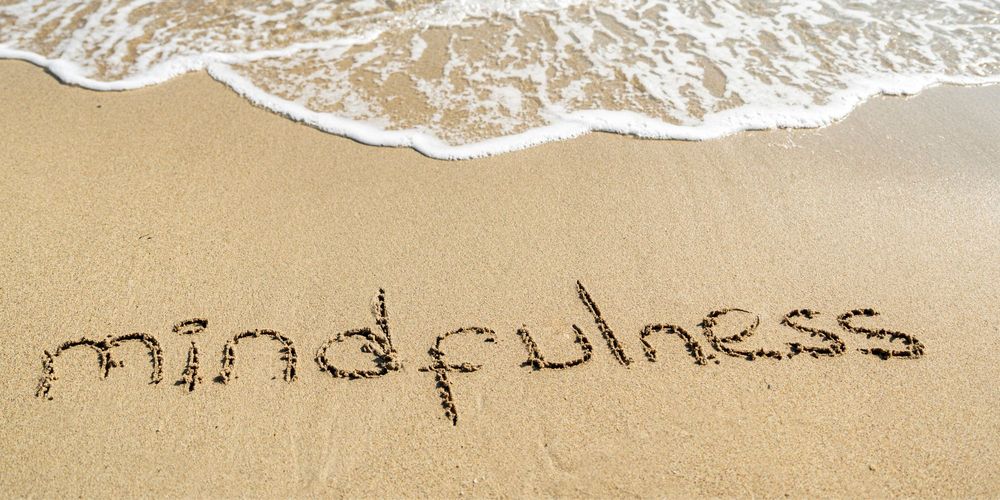 a beach with mindfulness written in the sand