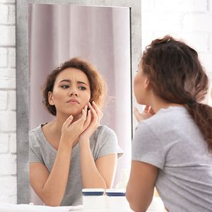 woman examining face in mirror