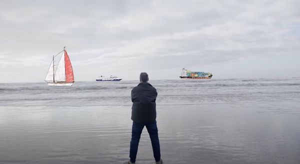 Man standing on beach watching boats go by