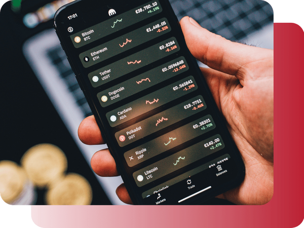 A person monitoring crypto exchange rates on a mobile phone with gold coins in the blurred background.