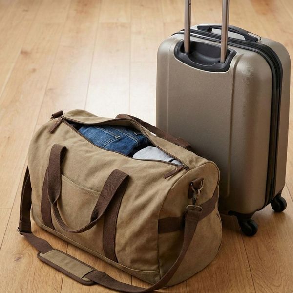 A packed duffel bag and suitcase on a floor.