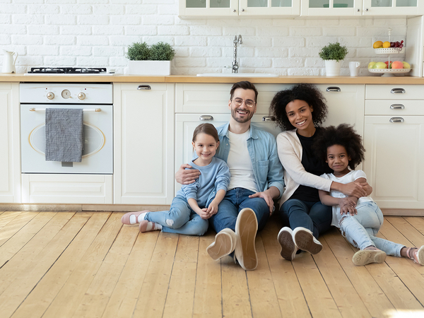 Family of four sitting on the floor in their home. 