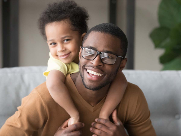 A man wearing glasses and a young boy hugging over his shoulder