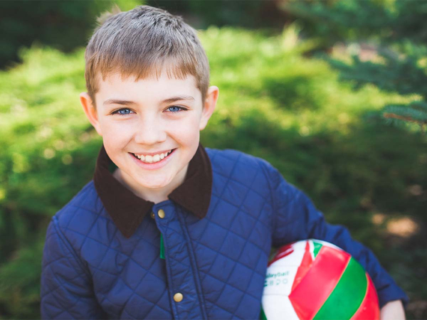 A young boy in a blue jacket with a ball