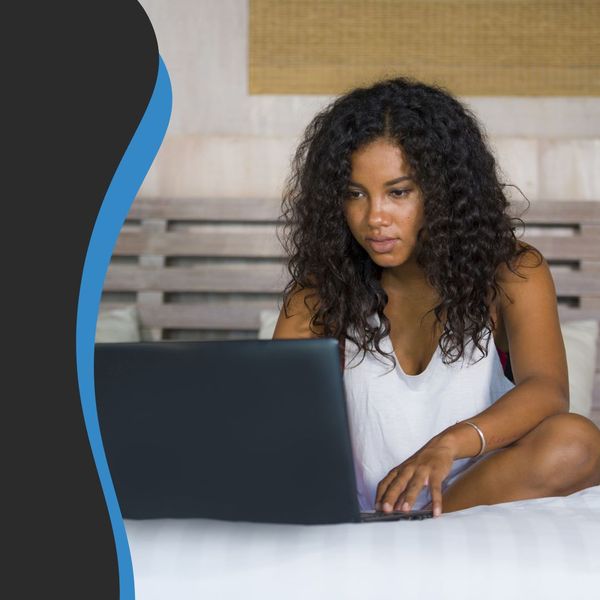 Image of a woman on her computer on her bed