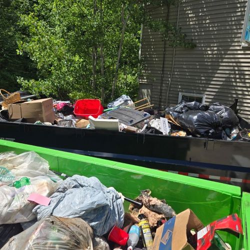 Green dumpster filled with trash and discarded items