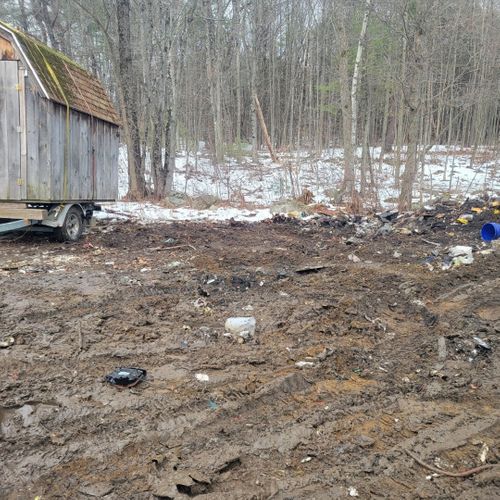 Muddy outdoor lot with an old wooden shed and light snow