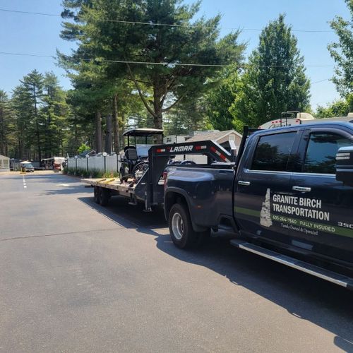 Black pickup truck hauling a loaded trailer on a residential street