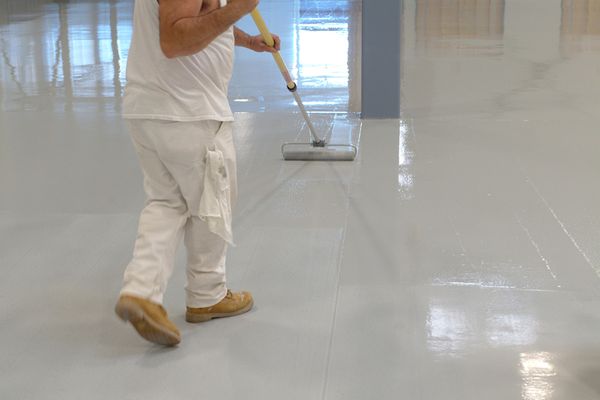 a person coating a concrete floor