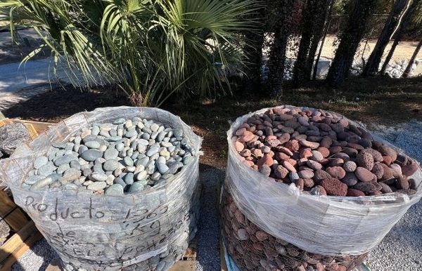 Large industrial bulk bags filled with assorted river rock and decorative landscape stones ready for professional project installation.