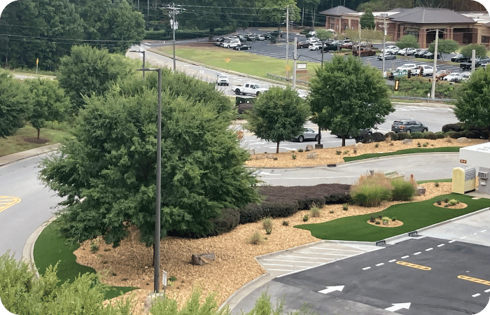 Aerial view of a parking lot with a landscaped island containing trees, shrubs, and turf.