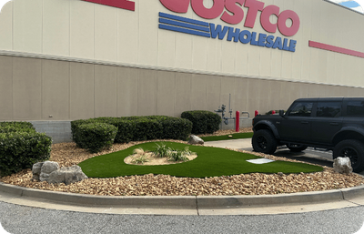 Landscaped area with artificial turf and rocks in front of a Costco Wholesale building