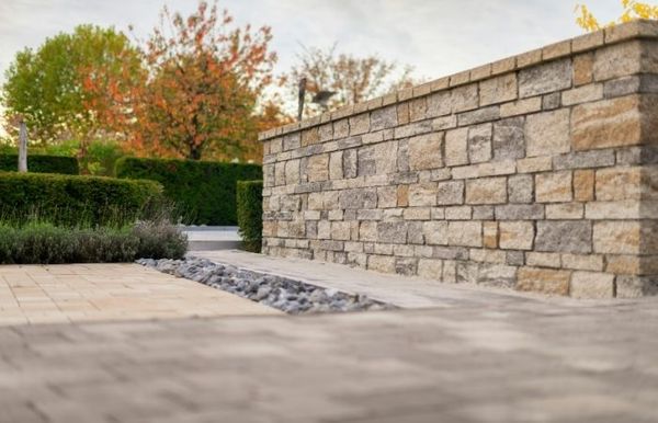 Expertly constructed natural stone retaining wall and decorative gravel drainage path integrated into a modern commercial landscape design.