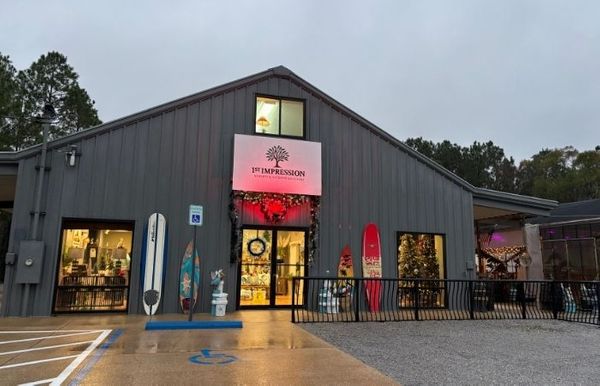 Exterior of a nursery building with a red door, display windows, and a sign.