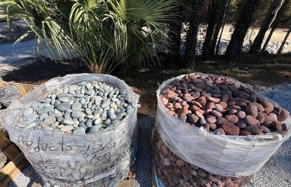 Large industrial bulk bags filled with assorted river rock and decorative landscape stones are ready for professional installation on projects.