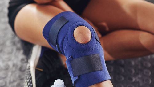 Woman with a knee injury in a brace in need of a massage to reduce swelling and provide relief.