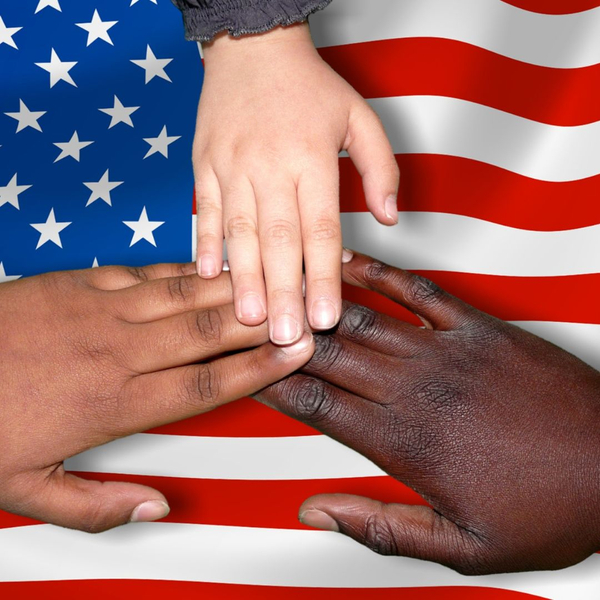 Three people putting their hands together on top of an American flag
