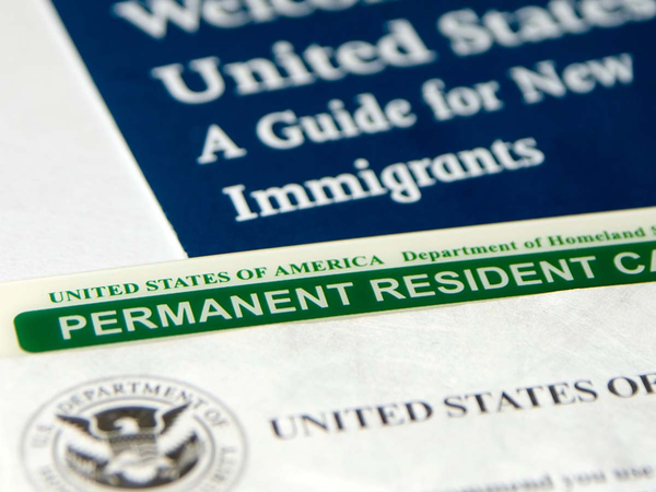 US permanent resident card (Green Card) seen with welcome to the USA brochure 