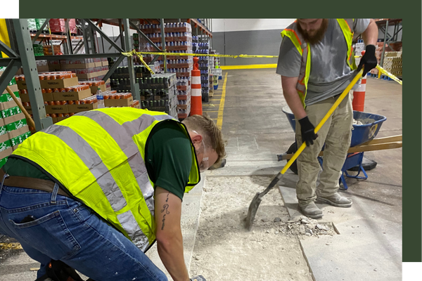 2 workers fixing a concrete slab in a warehouse