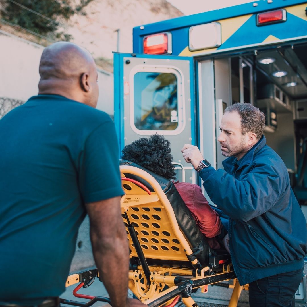 First aid responders loading an injured civilian to the back of an ambulance