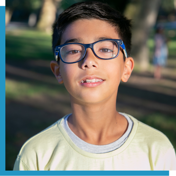 Young boy outdoors wearing blue-framed glasses