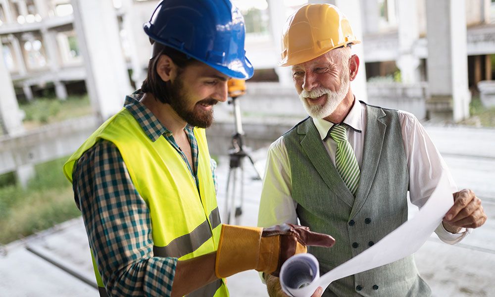 two males in hard hats looking over blueprints