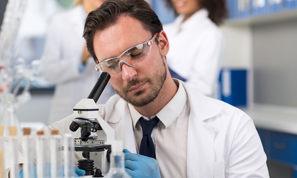 man wearing safety glasses looking into stethoscope