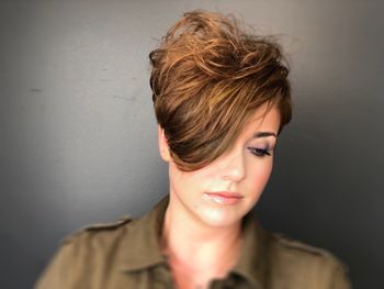 Woman with styled brown, highlighted hair standing in front of a gray background at THE LONDONER in Hermosa Beach.