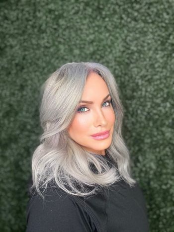 Woman with styled gray hair standing in THE LONDONER's outdoor hair salon after an appointment.
