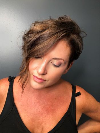 Woman with short, styled brown hair standing in front of a gray wall at THE LONDONER in Hermosa Beach.