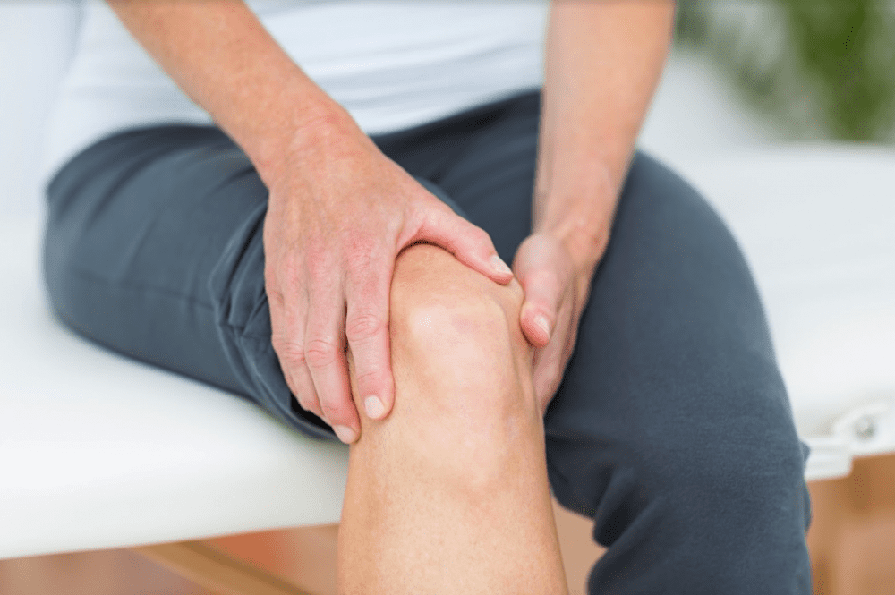 person holds their knee like it is painful