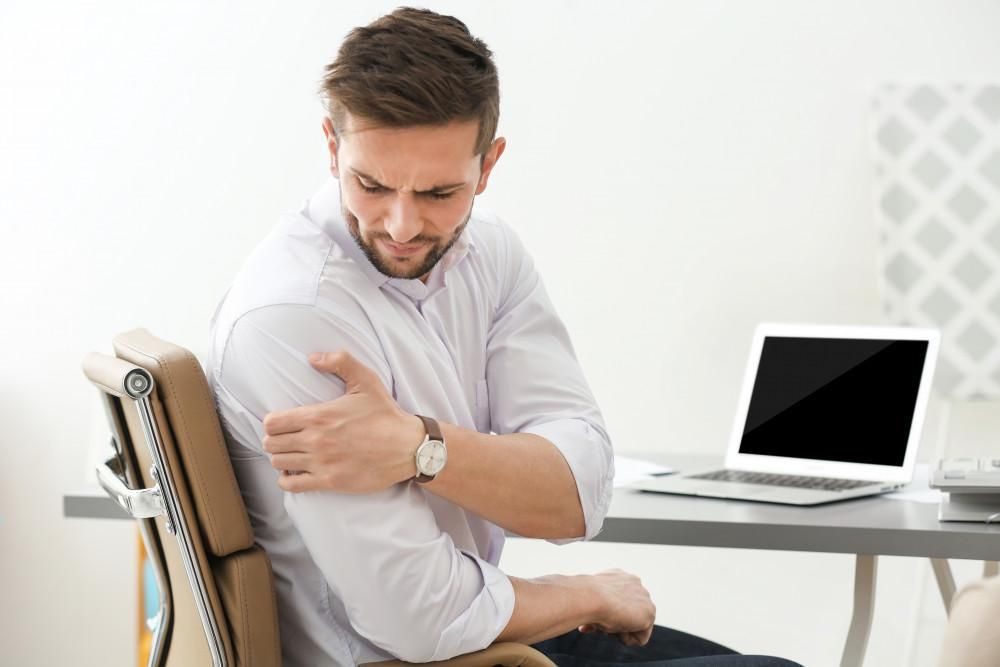 man holds his shoulder like it hurts