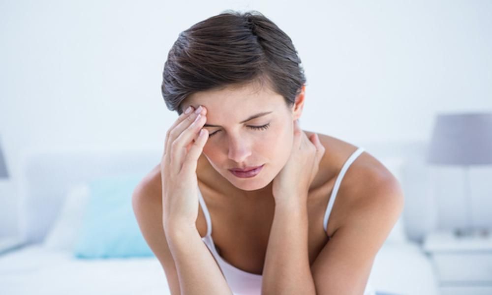 woman holds her head and neck in pain