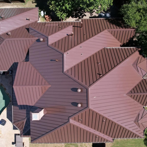 Bird's-eye view of a complex residential roofing project featuring multiple valleys and peaks finished in matte brown metal.