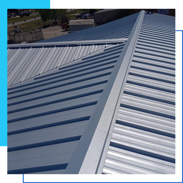 Close-up view of a light grey PBR metal roof installation showing the ridge cap and durable ribbed panels.