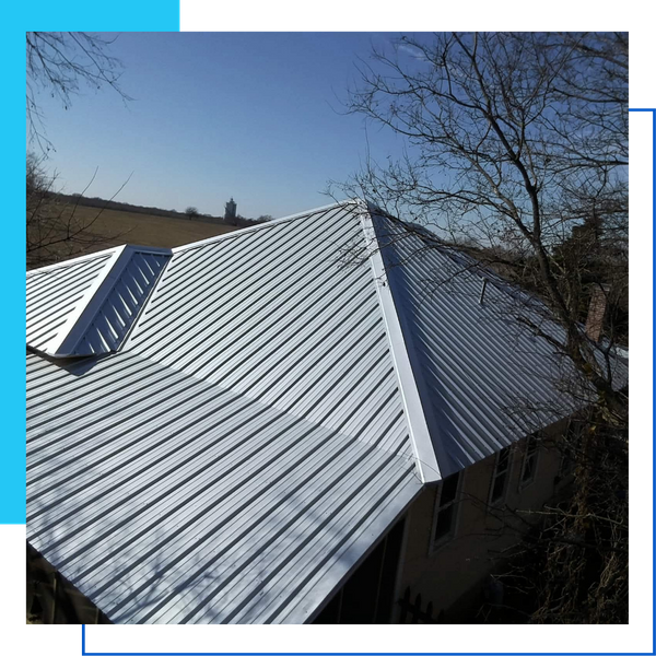 High-angle view of a complex residential roof with multiple peaks finished in bright silver ribbed metal.